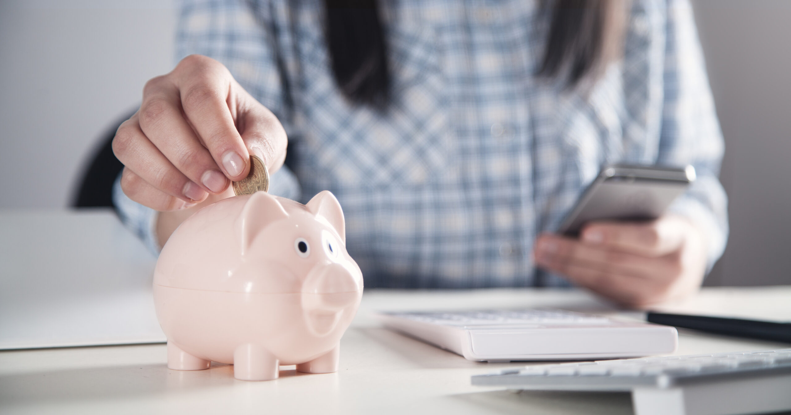 Simple Ways To Spend Less: Women putting money into a piggy bank